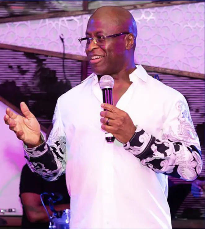 Mo wearing a decorative dress shirt, smiling during his speech