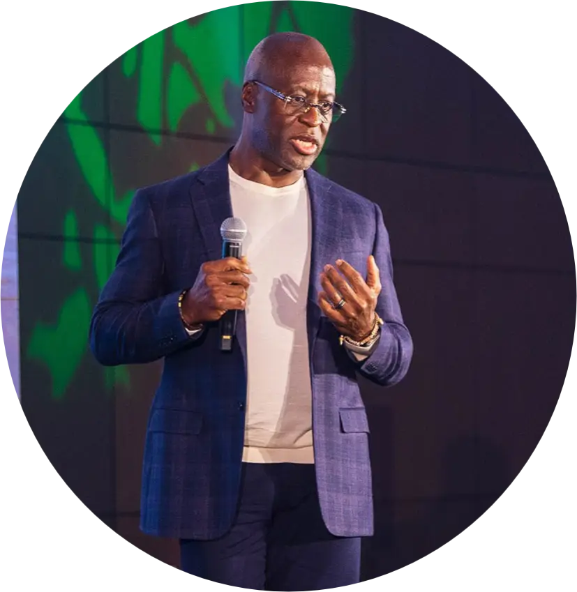 Mo Landy on stage, wearing a navy sport coat over a white t-shirt, holding a microphone