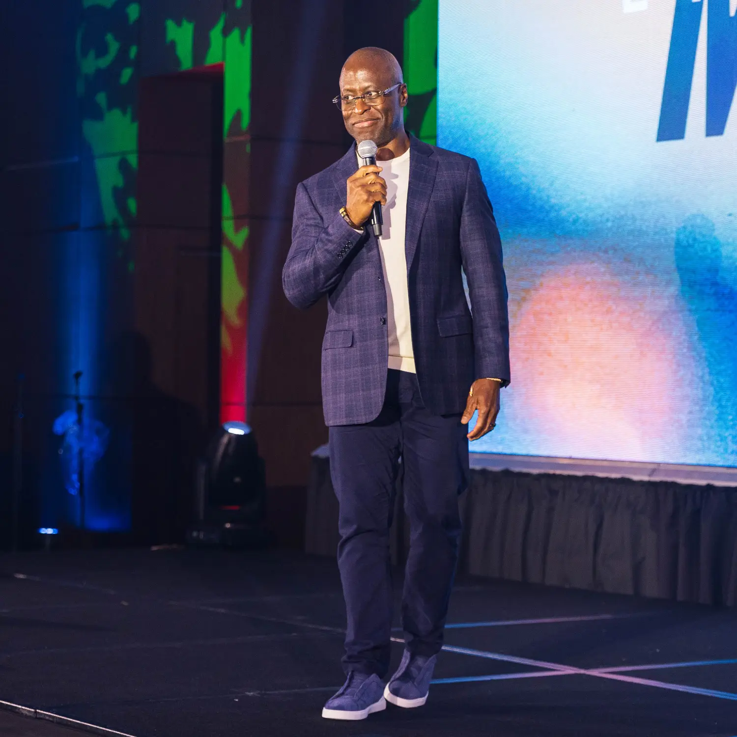 Morace smiling on stage with a microphone in hand